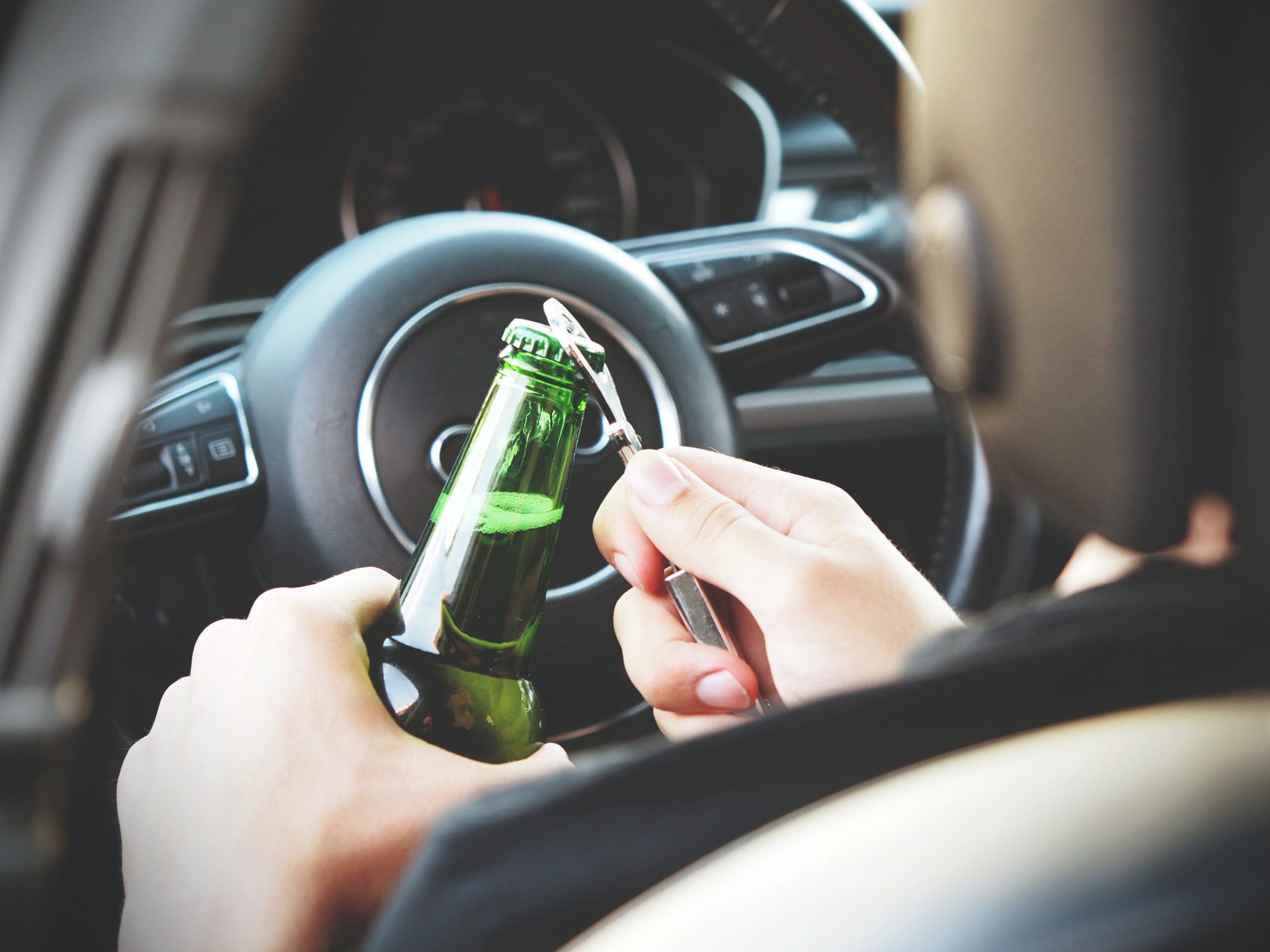 Person opening beer bottle in car