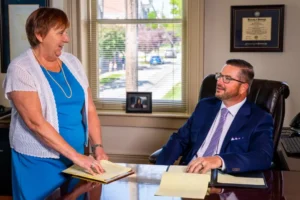 Lawyer Bryan S. Neiderhiser at his desk having a consultation with a team member