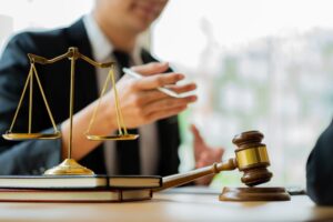 Wrongful death lawyer at desk with scales of justice and hammer, symbolizing legal work for justice.