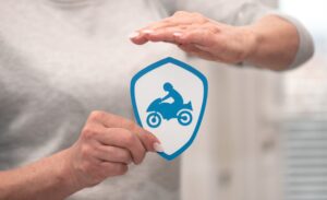 Female hand holding a paper shield, symbolizing motorbike insurance concept