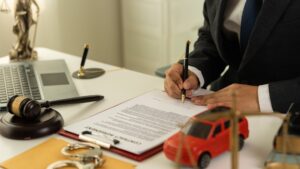 Car accident lawyer in courtroom with gavel and toy car models, representing insurance and court claims.