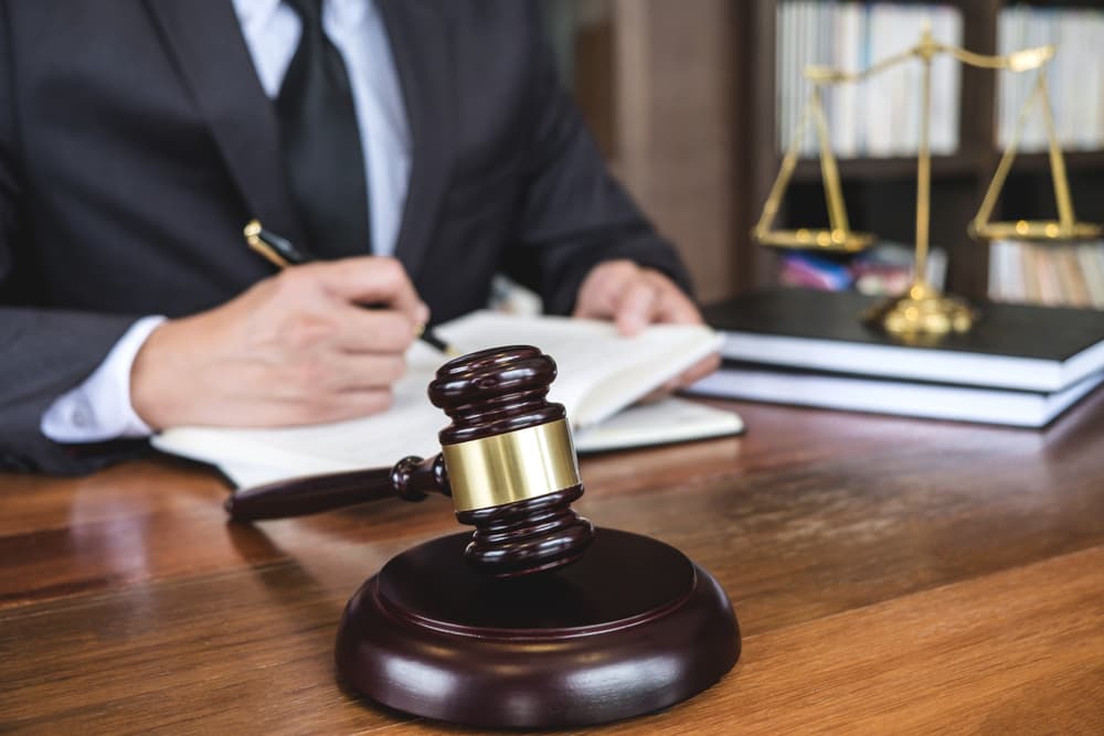 Judge's gavel with lawyers in suits reviewing legal documents in a courtroom, symbolizing law, legal advice, and justice.