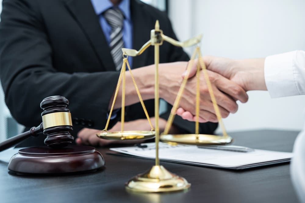 Male lawyer shakes hands with a client after a successful negotiation in a courtroom, symbolizing a positive outcome and cooperation.