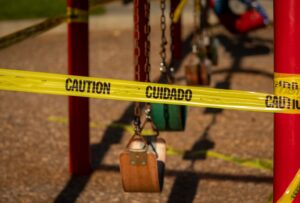 A playground area is taped off with "Caution" tape, indicating a hazardous location for potential premises liability accidents.