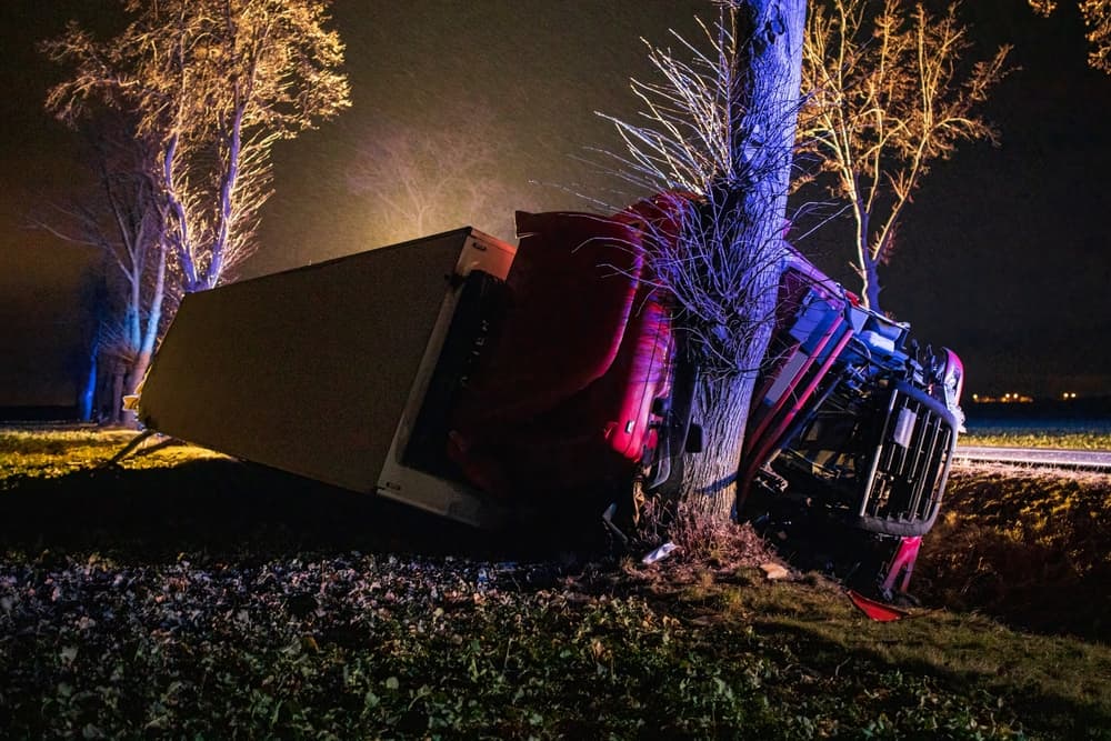 A truck crashed into a tree at night, symbolizing a potential truck accident claim process involving damages.