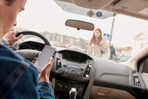 A driver distracted by their phone narrowly misses a pedestrian, highlighting potential liability in accidents.